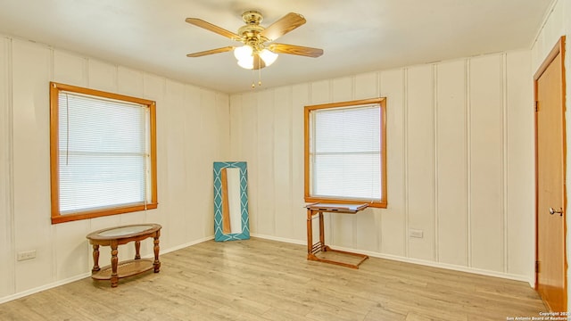 spare room featuring ceiling fan, light wood finished floors, and a decorative wall