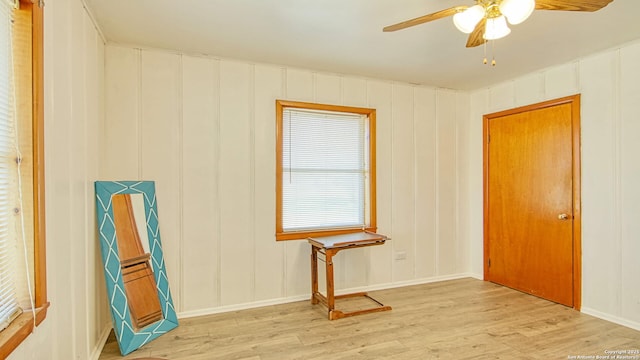 empty room featuring light wood-style floors, a decorative wall, and a ceiling fan