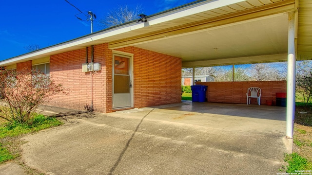 exterior space featuring a carport, brick siding, and driveway