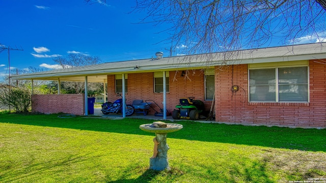 rear view of property with brick siding and a yard