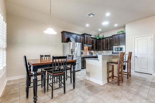 kitchen with tasteful backsplash, visible vents, a breakfast bar, stainless steel appliances, and under cabinet range hood