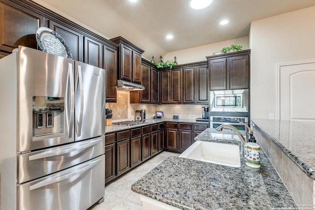 kitchen with stainless steel appliances, backsplash, a sink, dark brown cabinetry, and under cabinet range hood