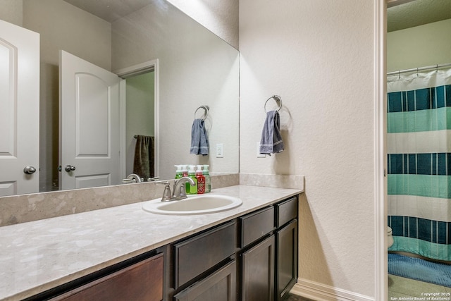 bathroom with baseboards, a textured wall, toilet, a shower with curtain, and vanity