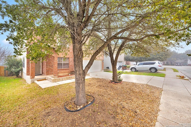 view of yard with an attached garage, fence, and concrete driveway