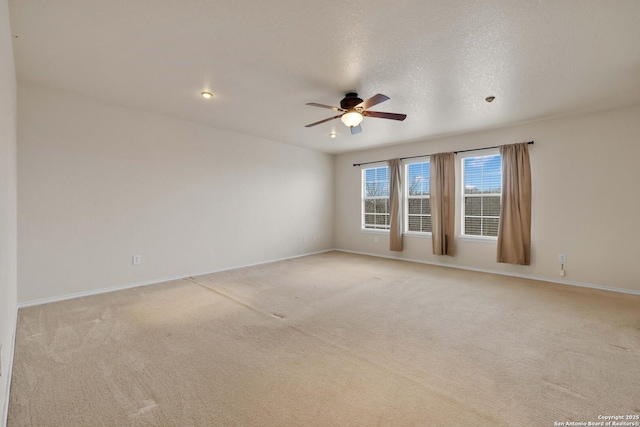 unfurnished room with light carpet, ceiling fan, a textured ceiling, and baseboards