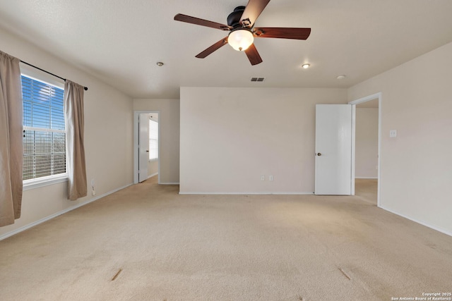 unfurnished room with a ceiling fan, light carpet, visible vents, and baseboards