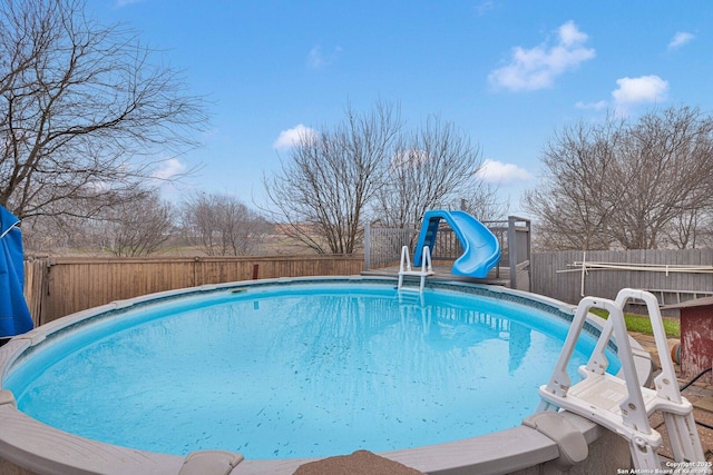 view of swimming pool with a fenced in pool, a water slide, and a fenced backyard