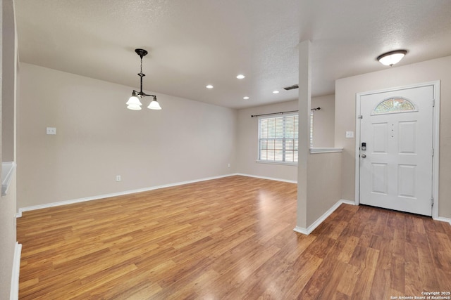 entrance foyer with light wood finished floors, baseboards, and a textured ceiling