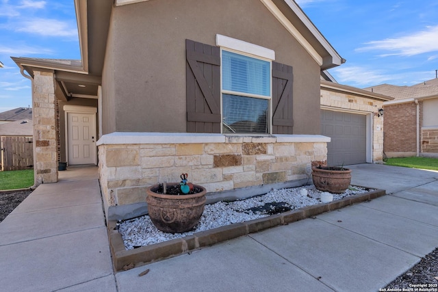 view of front facade with stone siding, driveway, an attached garage, and stucco siding