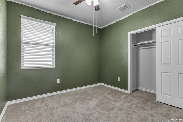 unfurnished bedroom featuring a closet, visible vents, a textured wall, carpet flooring, and baseboards