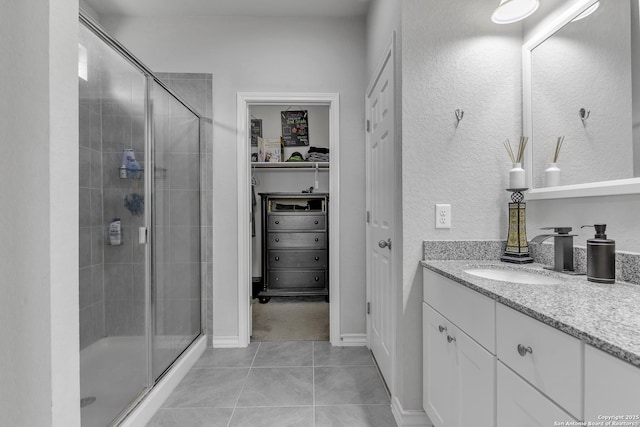 full bathroom featuring tile patterned flooring, a shower stall, vanity, and a spacious closet