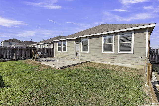 rear view of house featuring a lawn, a patio area, and a fenced backyard