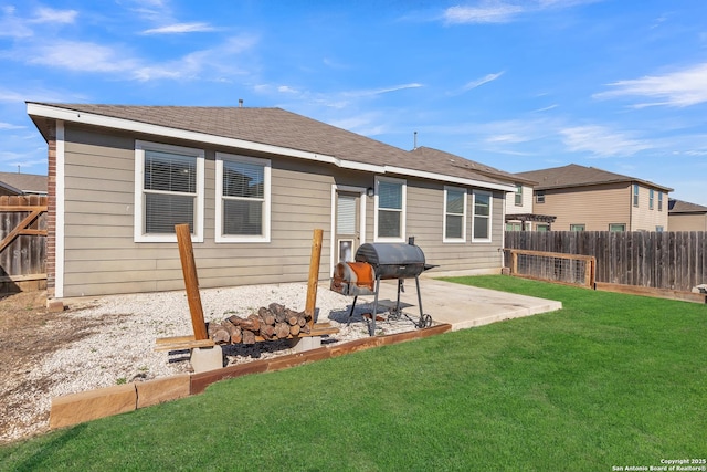 rear view of house with roof with shingles, a patio, fence, and a lawn