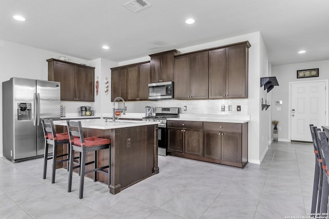 kitchen featuring tasteful backsplash, visible vents, appliances with stainless steel finishes, a sink, and dark brown cabinetry