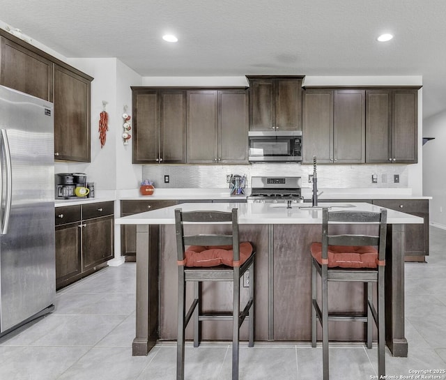 kitchen with stainless steel appliances, a breakfast bar, dark brown cabinetry, and decorative backsplash