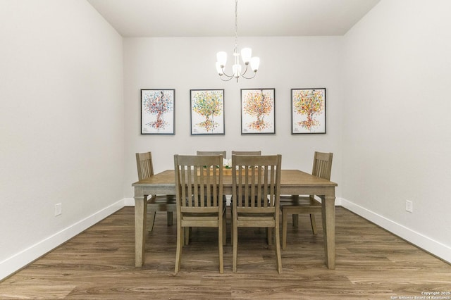 dining space featuring baseboards, a chandelier, and wood finished floors