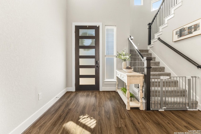 foyer entrance with stairs, baseboards, and wood finished floors