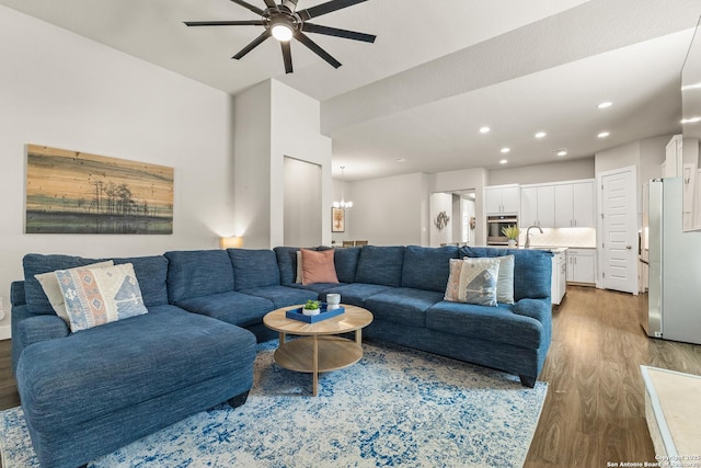 living room featuring ceiling fan with notable chandelier, wood finished floors, and recessed lighting