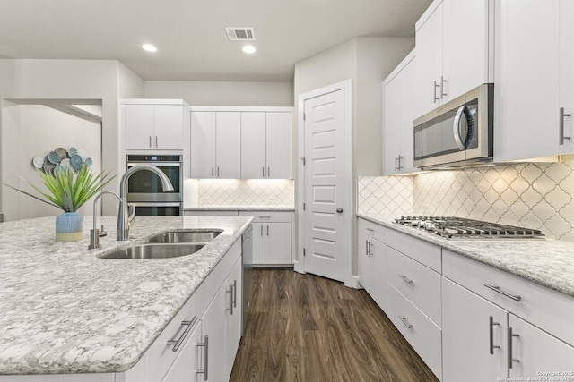 kitchen with stainless steel appliances, a sink, visible vents, white cabinets, and dark wood-style floors