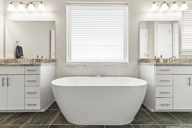 bathroom with a sink, a freestanding tub, and two vanities