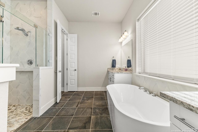 full bathroom with a freestanding tub, vanity, visible vents, baseboards, and walk in shower