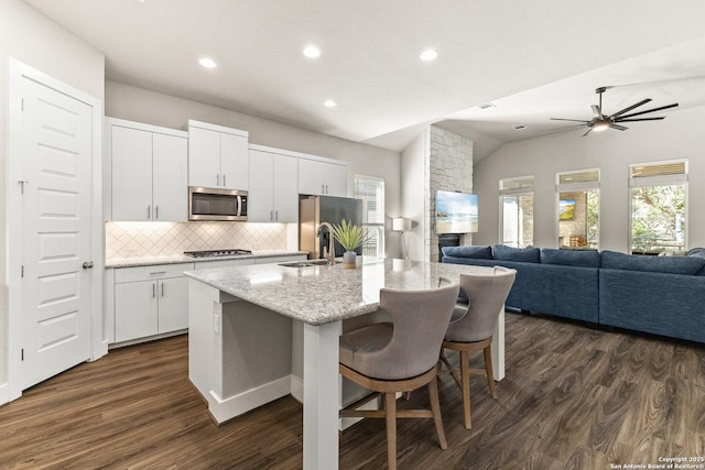 kitchen featuring appliances with stainless steel finishes, dark wood finished floors, a kitchen island with sink, and white cabinetry