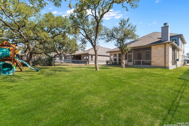 view of yard featuring a sunroom, a playground, and a fenced backyard