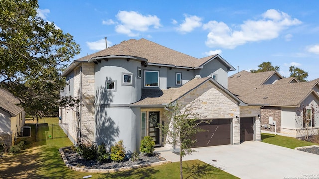 view of front of home featuring a garage, concrete driveway, stone siding, fence, and a front lawn