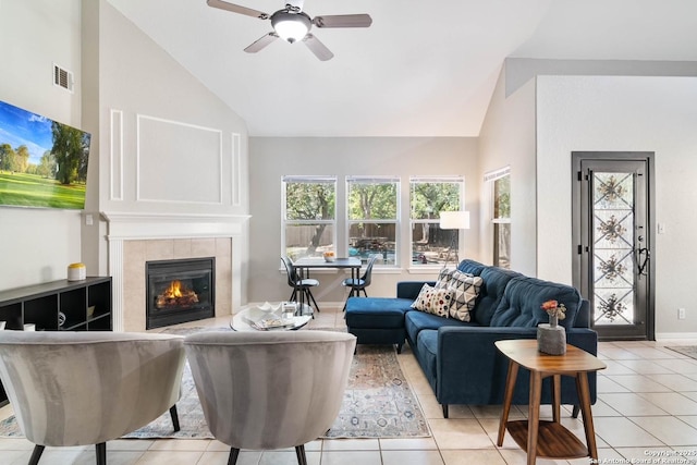 living area featuring light tile patterned floors, baseboards, visible vents, a ceiling fan, and a tile fireplace