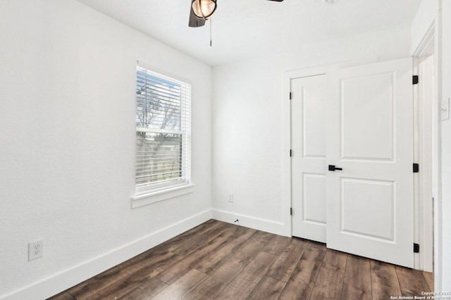 unfurnished bedroom featuring dark wood-style floors, a ceiling fan, and baseboards