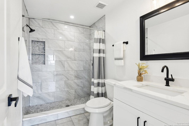 full bathroom featuring visible vents, a tile shower, vanity, and toilet