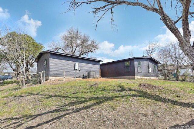 view of side of home featuring fence, a lawn, and central air condition unit