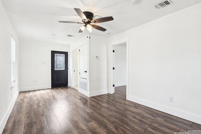 spare room featuring baseboards, visible vents, and dark wood finished floors