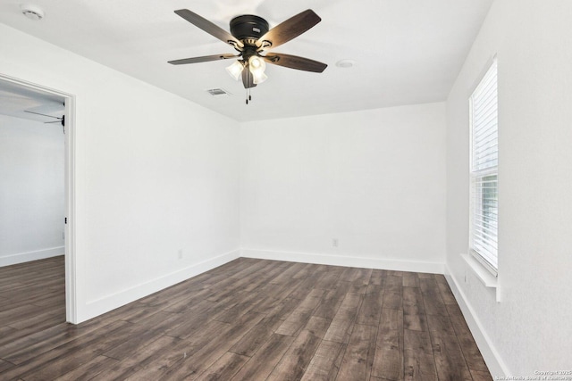 empty room featuring ceiling fan, dark wood finished floors, visible vents, and baseboards