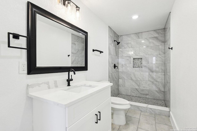 bathroom with toilet, tiled shower, and vanity