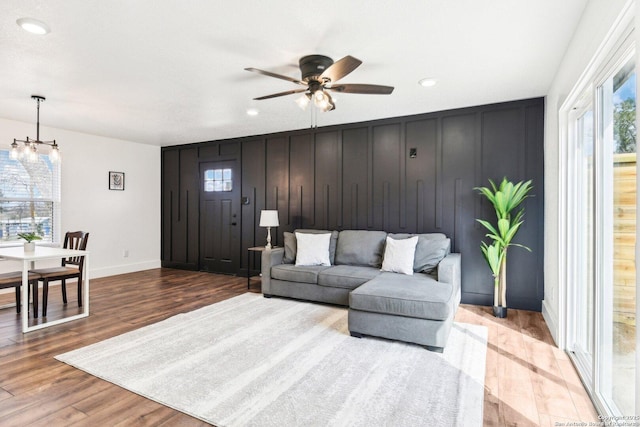 living area featuring ceiling fan with notable chandelier, recessed lighting, wood finished floors, and baseboards