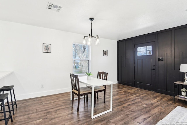 dining space featuring dark wood-style floors, a chandelier, visible vents, and baseboards