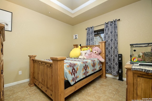 bedroom with a tray ceiling, light tile patterned floors, and baseboards