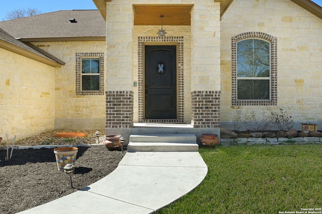 entrance to property with brick siding, stone siding, and a shingled roof