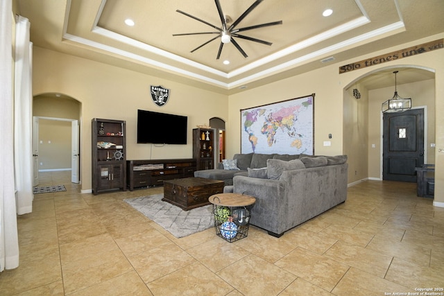 living area featuring arched walkways, baseboards, a raised ceiling, and a towering ceiling