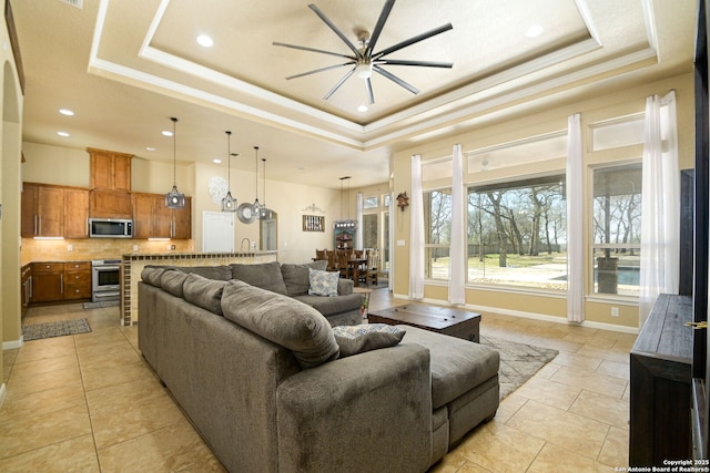 living area featuring recessed lighting, baseboards, a tray ceiling, and ceiling fan