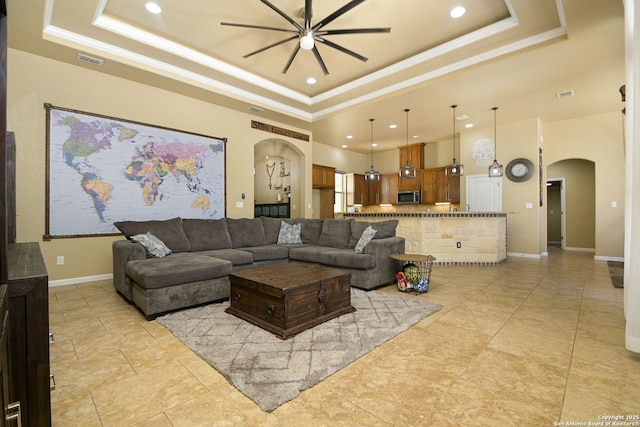 living area with visible vents, arched walkways, and a raised ceiling