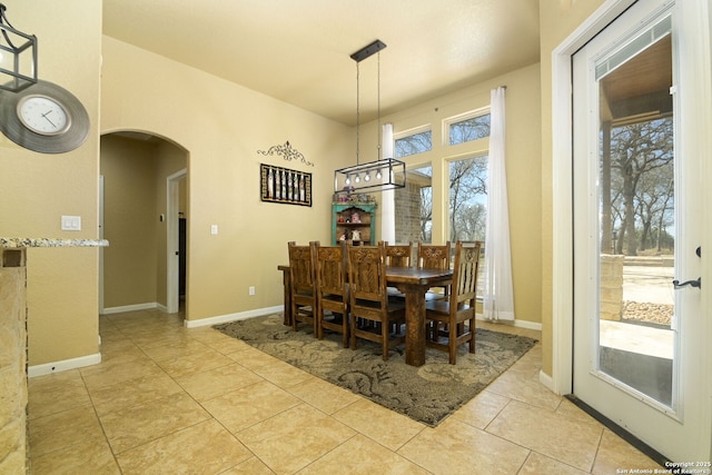 dining area featuring light tile patterned floors, baseboards, and arched walkways