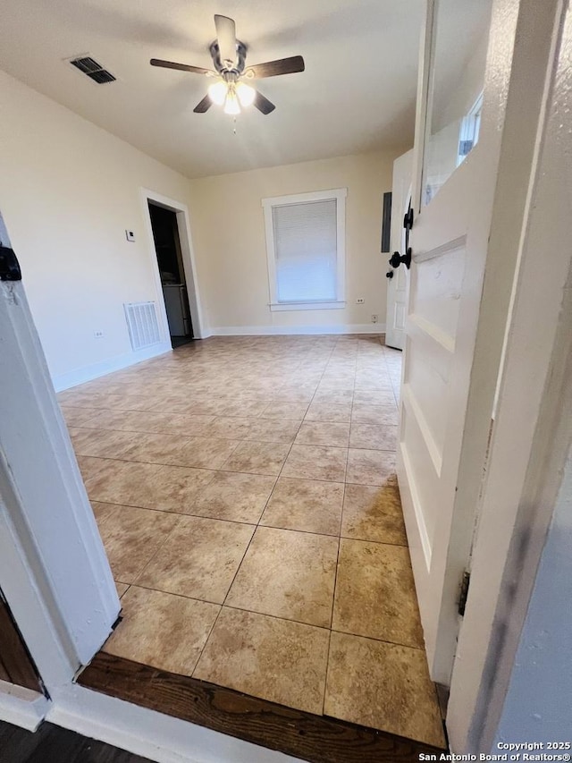 interior space featuring baseboards, light tile patterned flooring, visible vents, and a ceiling fan