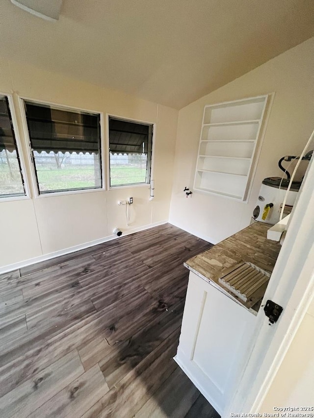 interior space with lofted ceiling, built in shelves, and dark wood finished floors