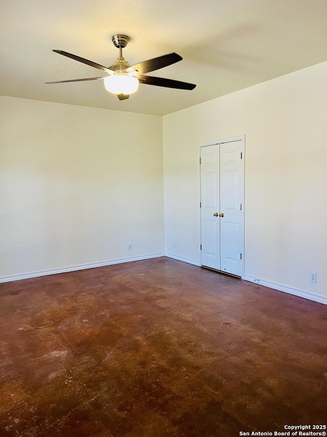 empty room with a ceiling fan, concrete floors, and baseboards