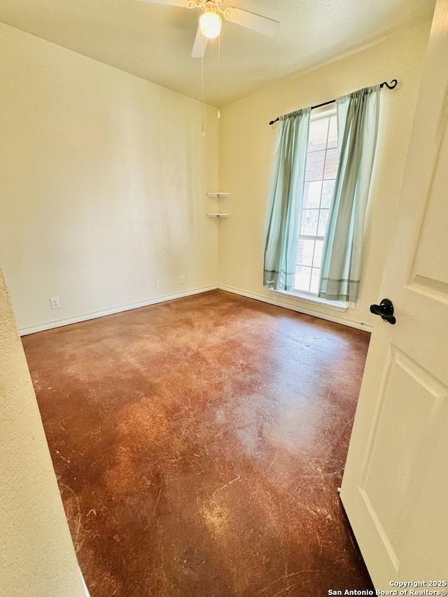 unfurnished room with ceiling fan, finished concrete floors, and baseboards