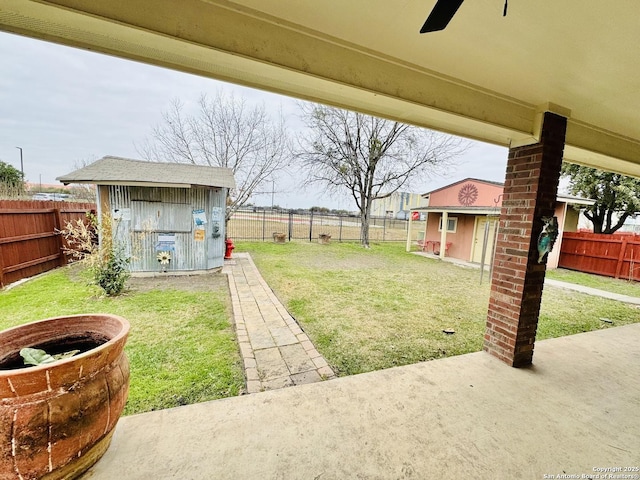 view of yard featuring an outbuilding, a fenced backyard, and ceiling fan