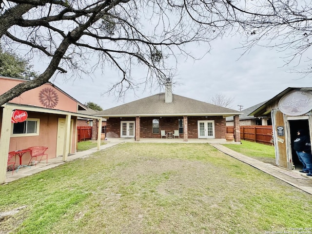 back of property with french doors, brick siding, fence, and a chimney