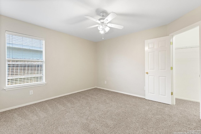 carpeted empty room with a ceiling fan and baseboards